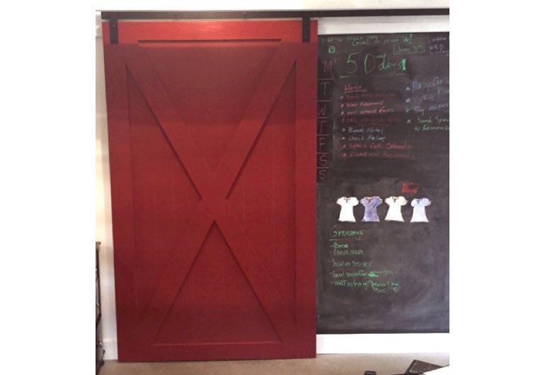 Bright red barn door with black hardware next to chalkboard 